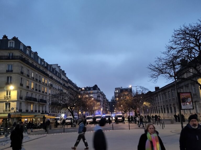 Police vans and a CRS cordon at Place de la Nation in Paris during a 2023 demonstration